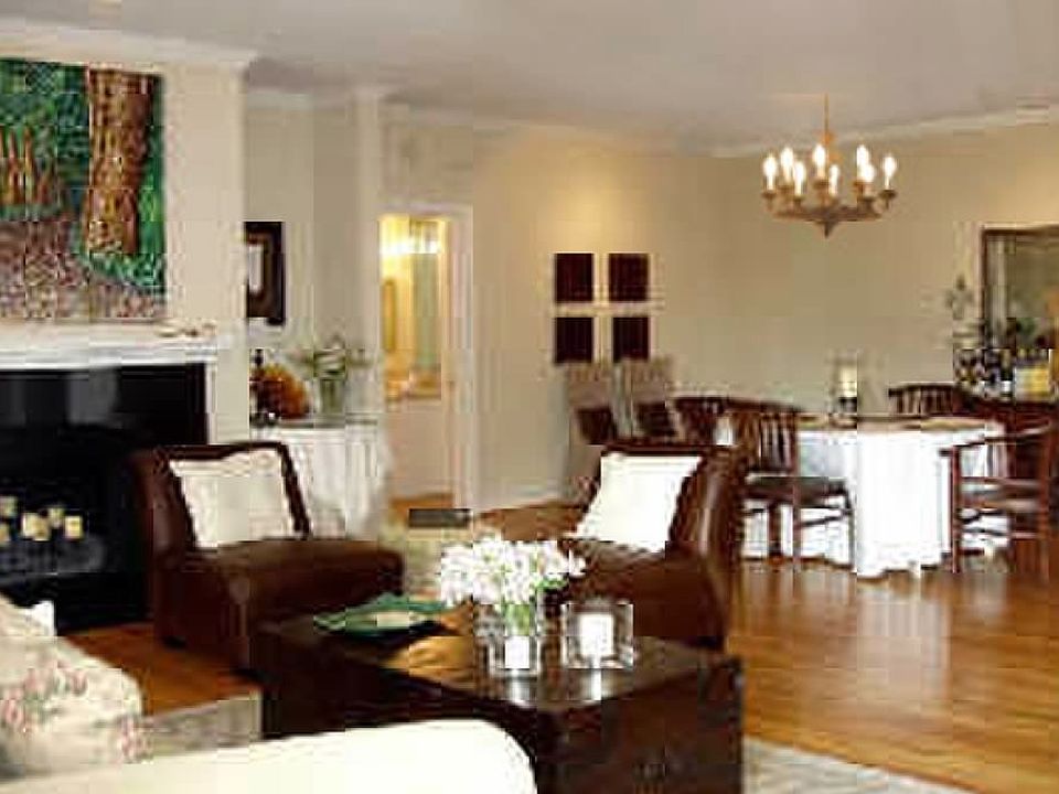 Expansive living and dining room with fireplace and wrought iron chandelier.