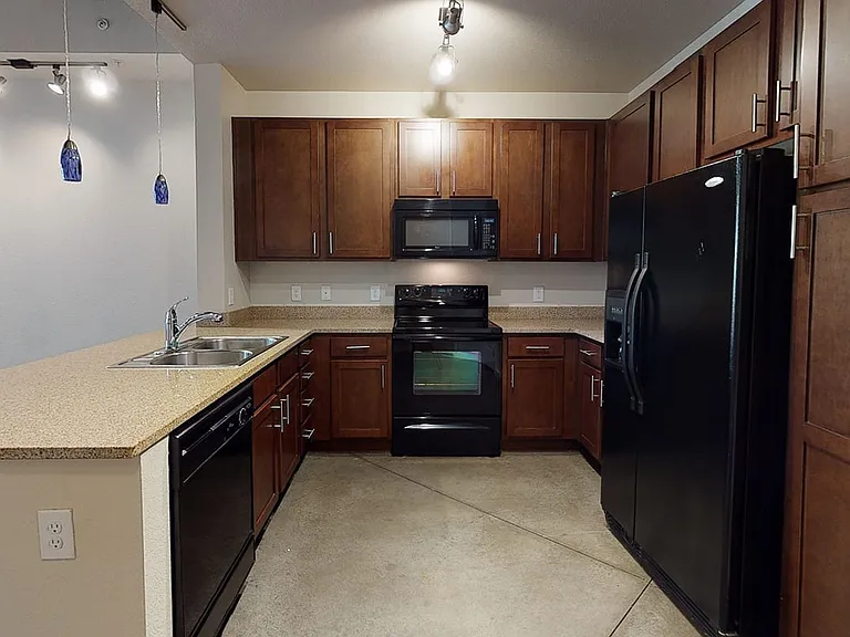 Apartment kitchen with granite countertops and polished concrete flooring.