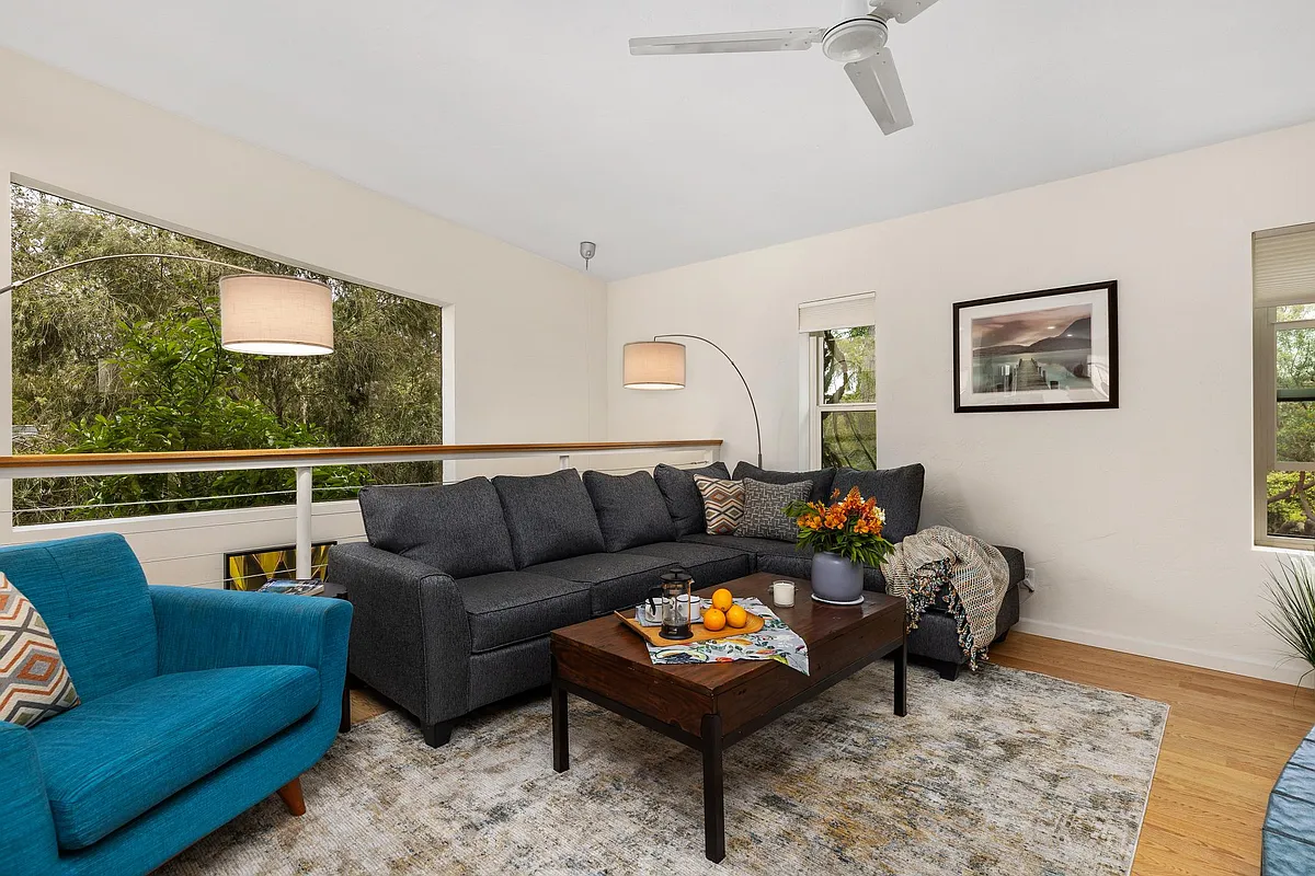 Light streams in through the huge picture window that offers views of the garden beyond. Cozy seating and mid-century styling make for a welcoming living room - 205 Cole Ranch Rd