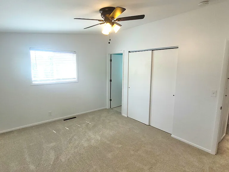 Large primary room with closet, ceiling fan, and primary bathroom
