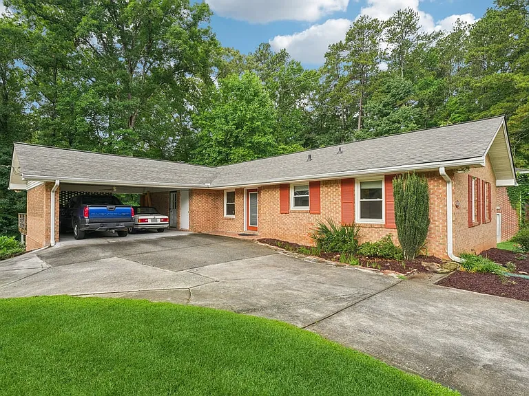 With its polished brick exterior, vibrant red shutters, manicured flower beds, and serene forest setting, this home offers a picture perfect blend of Southern charm and storybook tranquility.