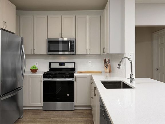 Renovated II kitchen with grey cabinetry, white quartz countertops, stainless steel appliances, white tile backsplash, and hard surface flooring