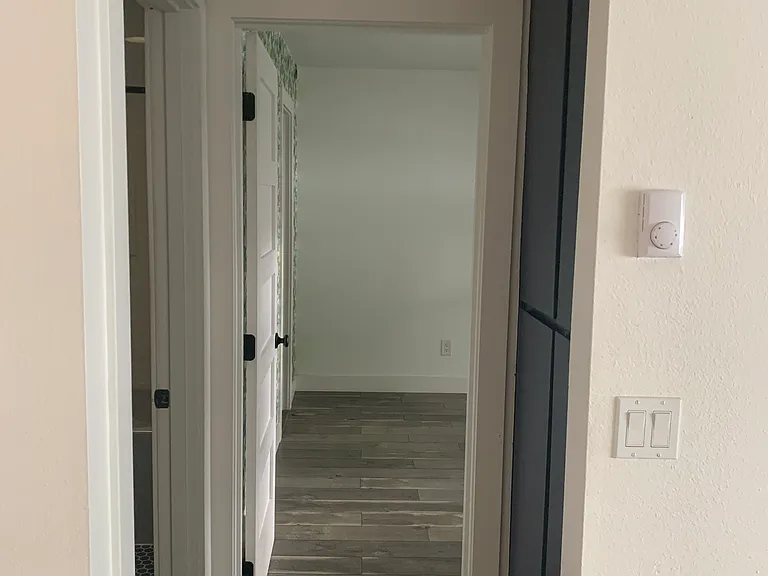 hallway from main room to bathrooom . bedroom, with tall storage closet on the right