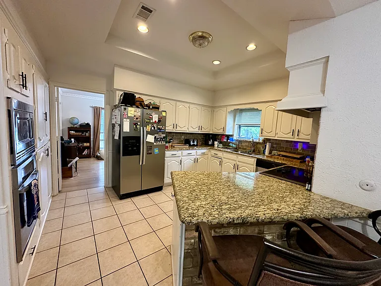 Kitchen with granite counters, decorative backsplash, a sink, light tile patterned floors, and stainless steel appliances