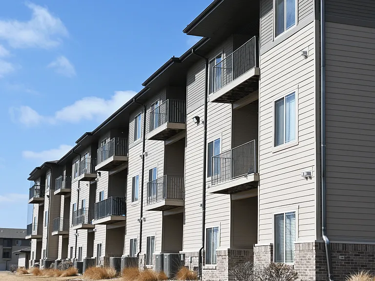 Apartment building with balconies and windows under a blue sky.