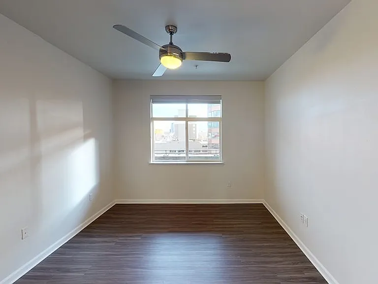 Spacious apartment bedroom with wood-style flooring.