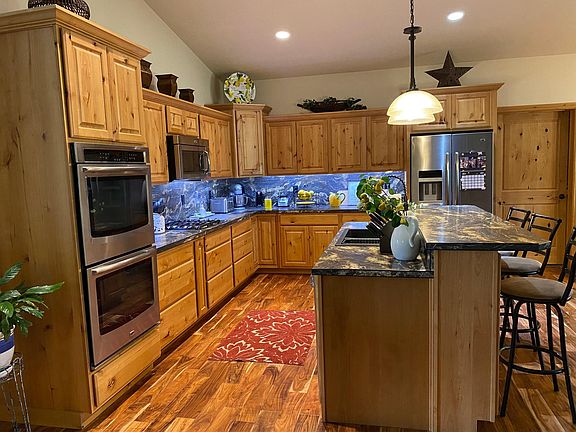 Kitchen with alder cabinets, under cabinet lighting, double ovens, stainless steel.