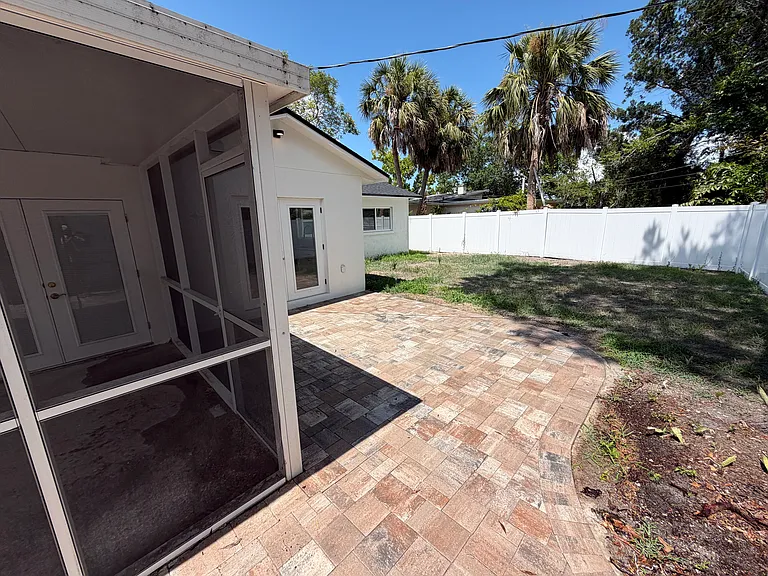 Backyard- pavers off kitchen and view of screened in patio from guest bedroom