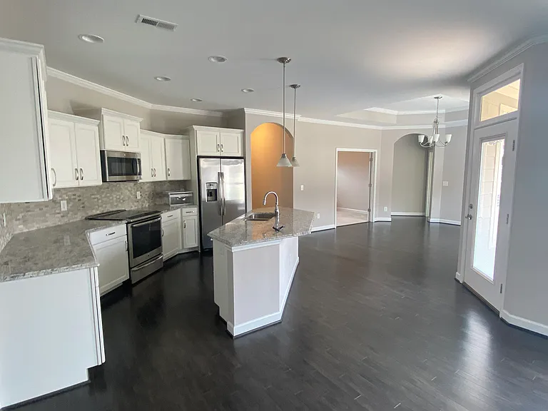 another view of the central kitchen and island towards the dining area and bedrooms