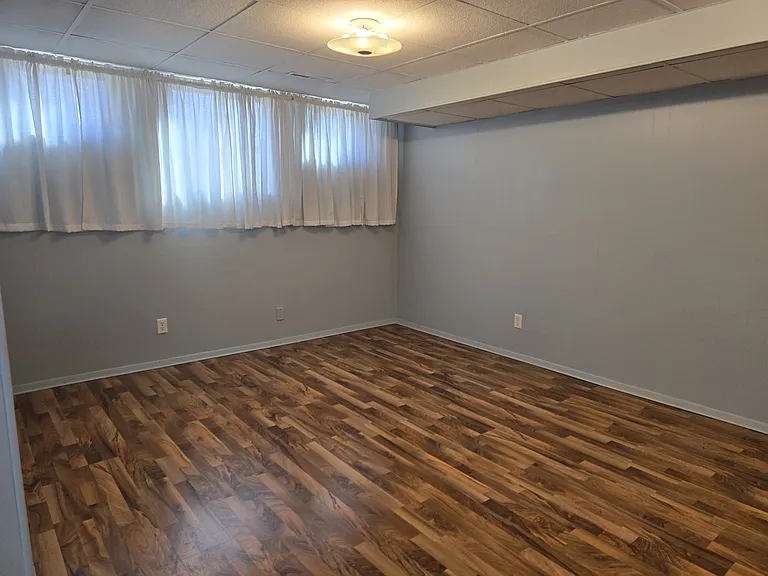 Living-dining room with wood-look laminate flooring, modern functional windows, overhead lighting