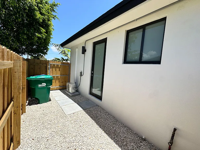 Private side yard with gravel ground cover, paver walkway, and fenced access to a rear entry door and window.