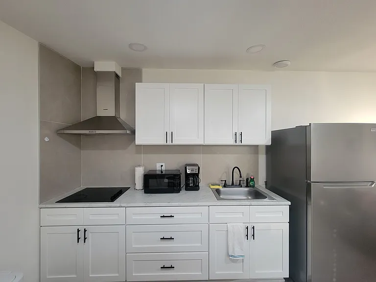 The kitchen includes a refrigerator, coffee maker, extractor hood and basic amenities.
