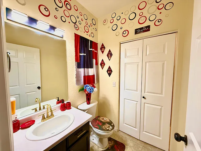 This stylish half bathroom offers a touch of luxury in a compact space. Adorned with red unique accent pieces, it's the perfect spot for a quick freshen-up. Plus, with convenient access to the laundry room, you can easily keep your clothes fresh and tidy.