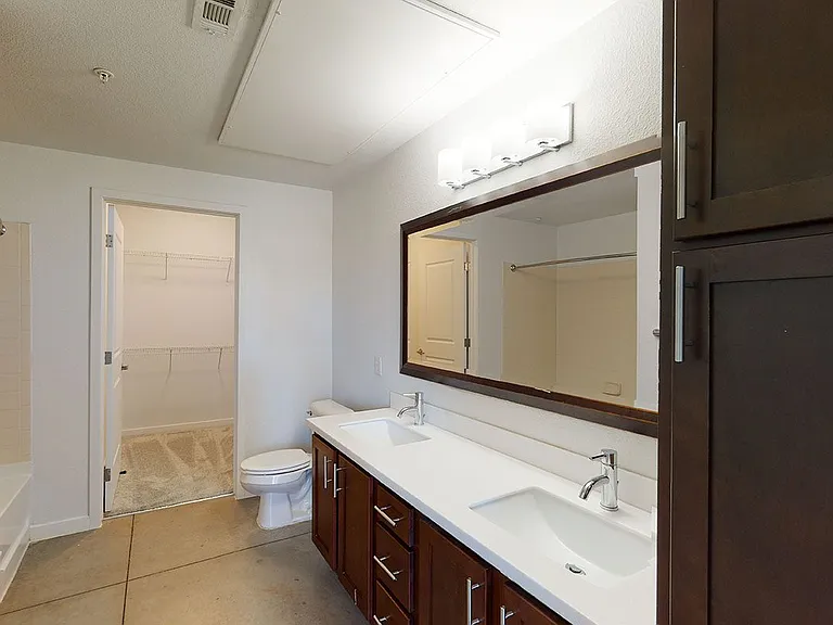 Apartment bathroom with polished concrete flooring and double sinks.
