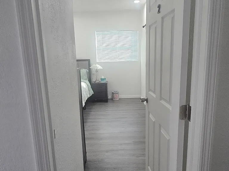 Private bedroom with durable wood-look flooring, a window for natural light, and space for a bed plus nightstand.