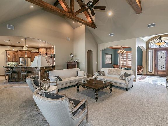 Living area with light colored carpet, visible vents, a notable chandelier, and arched walkways