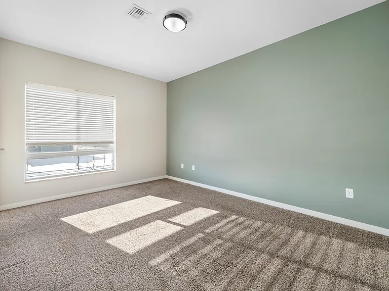 Bright and spacious bedroom with soft carpet, modern light fixture, and a large window letting in natural light. Bright and spacious bedroom with soft carpet, modern light fixture, and a large window letting in natural light.
