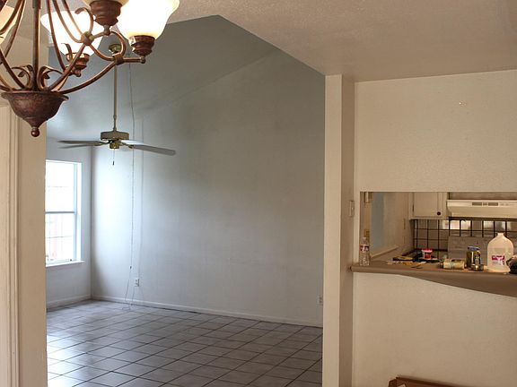 Living room cathedral ceilings opens to dining area, with bar and pass-through window to kitchen. Photo taken from dining area.