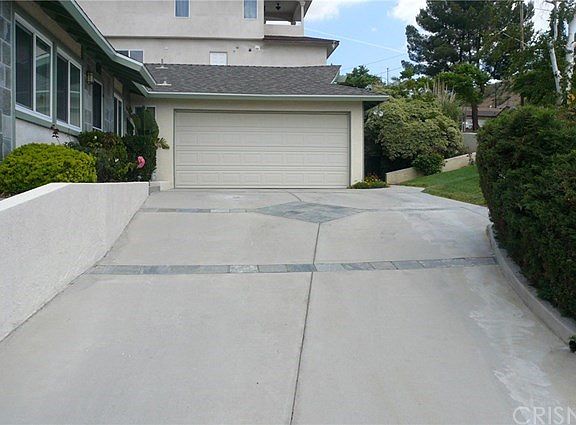Driveway to garage, door to house on left