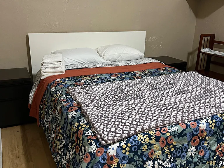 Furnished bedroom featuring a full-size bed with linens, nightstands, and convenient overhead cabinet storage.