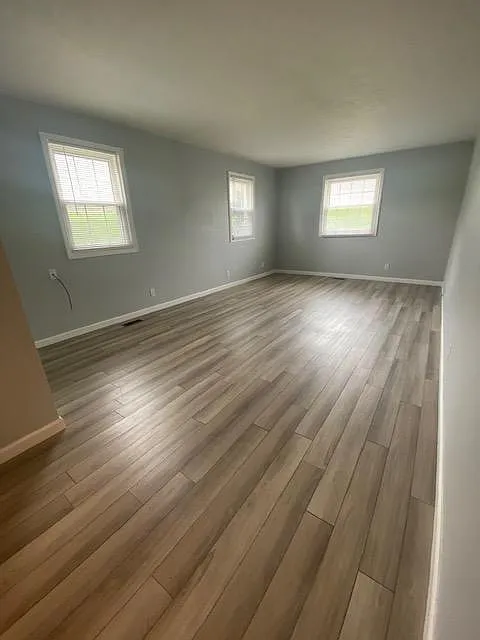 Living room with new vinyl floor and neutral walls. - 5710 Spotswood Dr