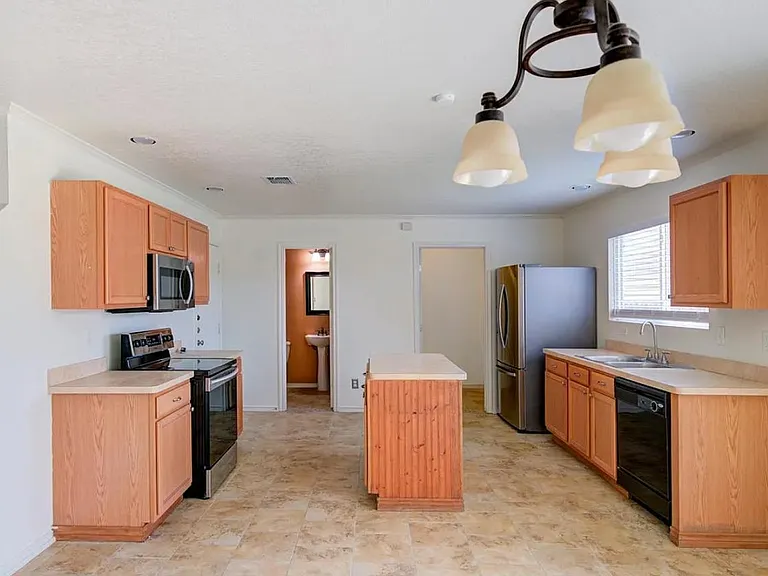 Spacious kitchen with center island, storage ,and a full appliance suite including dishwasher and microwave.
