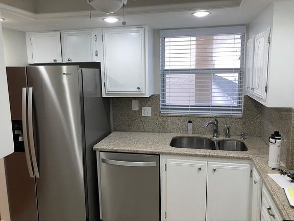Modern Kitchen with stainless steel appliances, granite countertops, stainless steel sink with garbage disposal, newer dish washer, range and refrigerator. Fan overhead with switched light. Area directly to the right for small table.