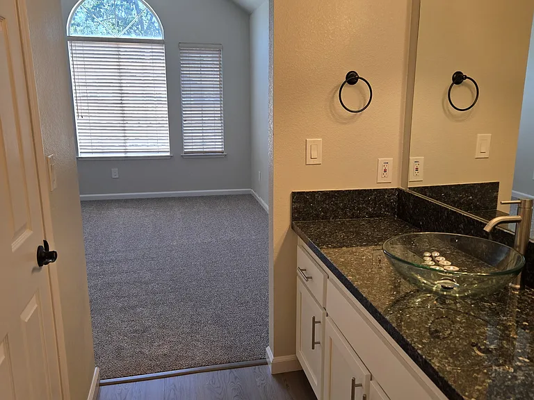 Remodeled primary en-suite features a granite vanity, designer glass vessel sink, updated lighting, and modern finishes throughout.