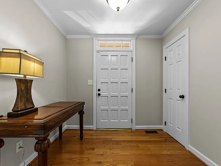 Hardwood foyer with transom window, fresh neutral walls, and convenient entry storage.