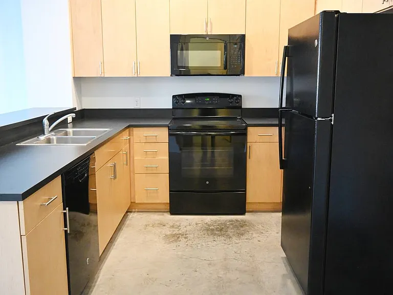 Kitchen with black appliances and counter at The Sawyer.