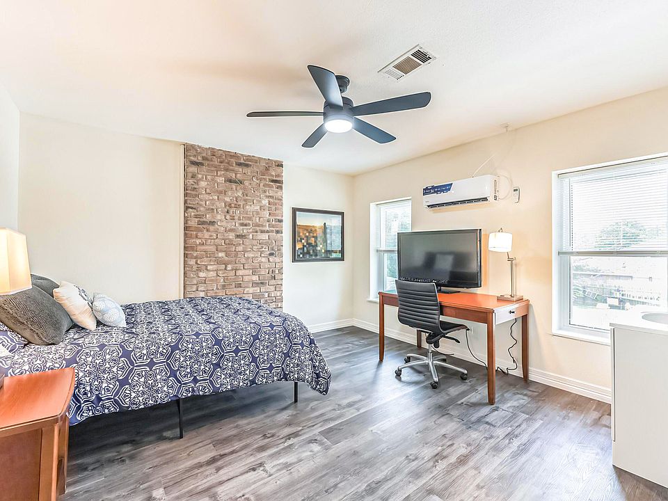 Upstairs room with minisplit AC, queen bed, hybrid mattress, night stand, full length mirror, and desk with chair and TV.
