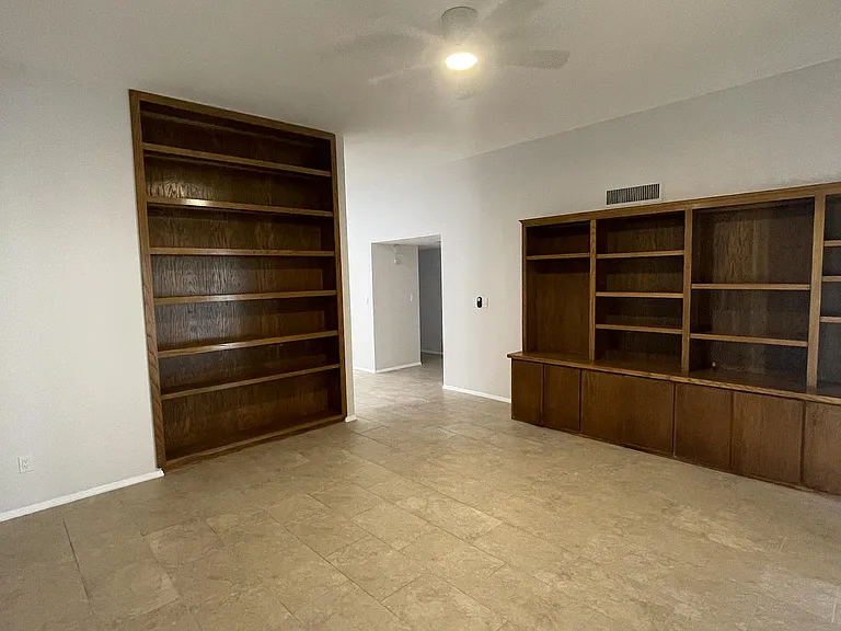 Den with built in bookshelves and sliding glass door to patio and pool