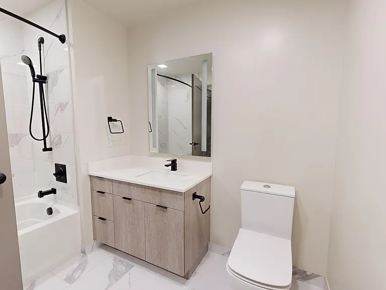 Apartment bathroom with tile flooring and LED vanity mirror.