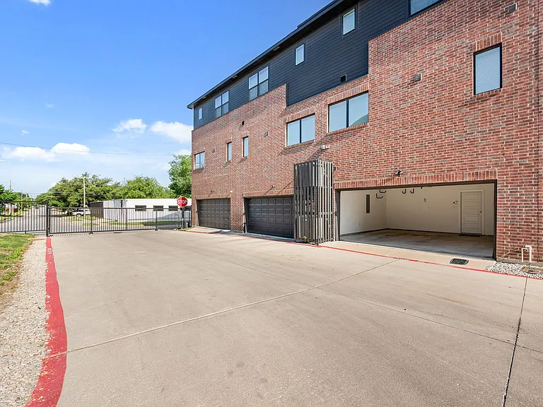 Exterior view of two-car garage (opened) from gated parking lot and street.