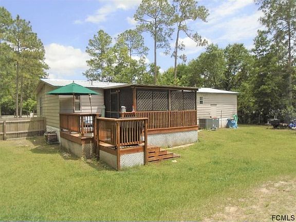 Back of home with grill deck leading to enclosed screen room.