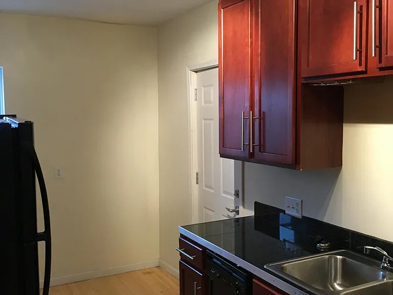 Opposite view in kitchen with sink/cabinets and door leading to fire escape and outdoor landing