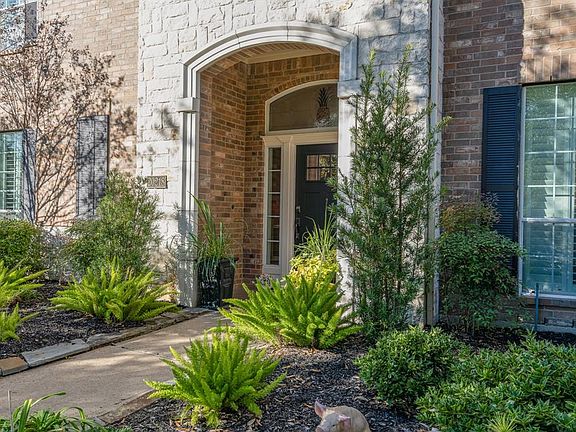 A brick and stone elevation is surrounded by lush landscape and mature trees making for great curb appeal!