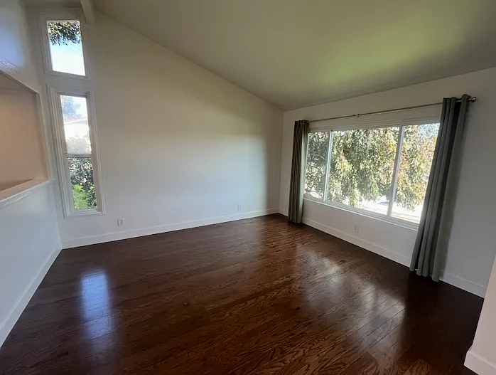 The living room features vaulted ceilings, abundant light, and oak wood floors.