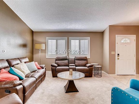 Cozy living room with vaulted ceilings and plantation shutters welcome you.