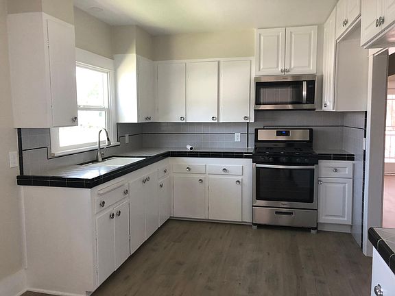 Kitchen with stainless steel stove and over the range microwave, vintage tile countertops, vinyl plank flooring