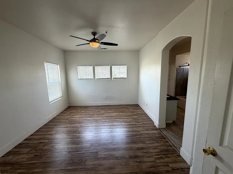 Spacious primary bedroom with ceiling fan and abundant natural light