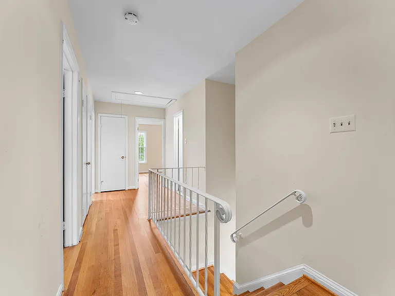 Stairs ascend to upper floor hallway with hardwood floors