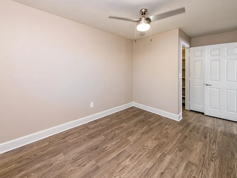 Find your peace in a spacious bedroom adorned with slick wood-style flooring.