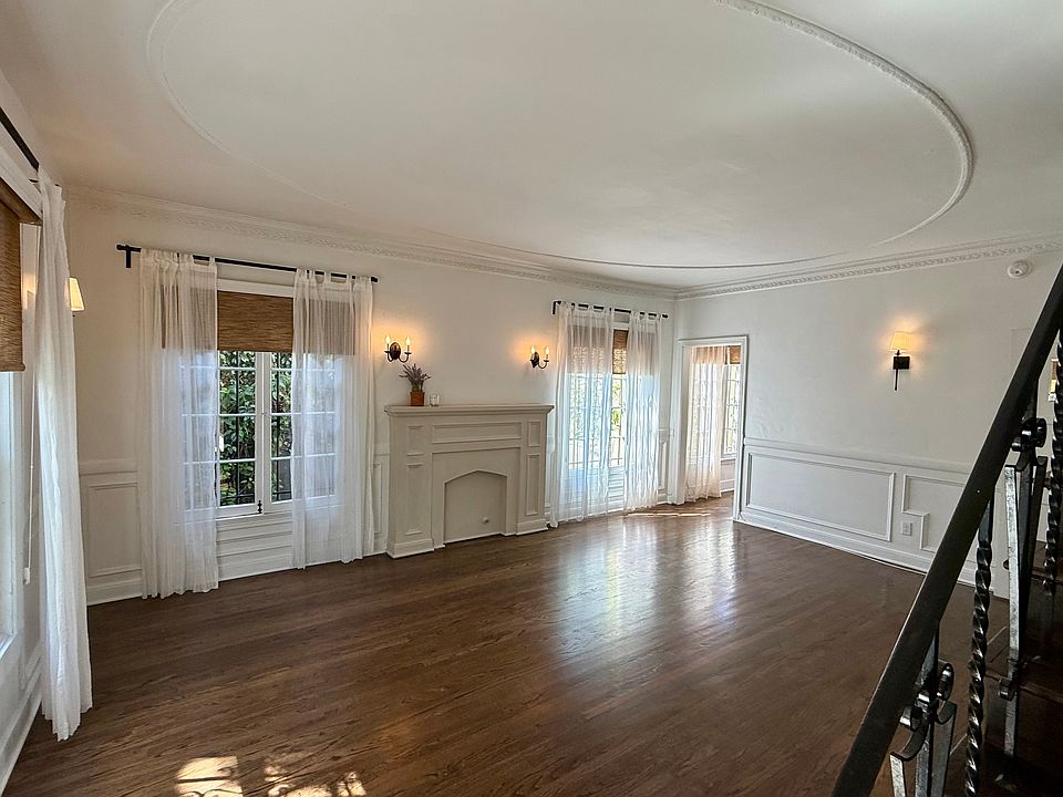 Stunning formal living room with wainscoting, high ceilings, faux fireplace, refinished hardwood floors, original character details throughout