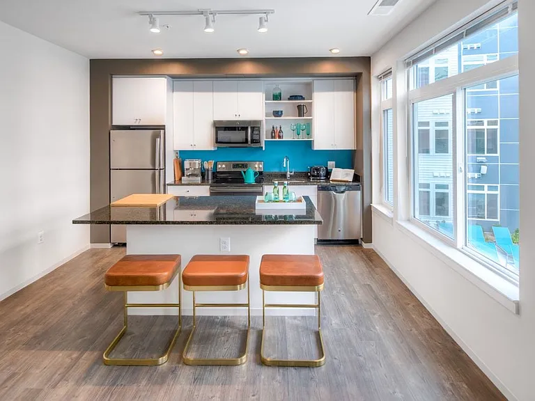 Kitchen with white cabinetry, granite countertops, island, stainless steel appliances and hard surface flooring