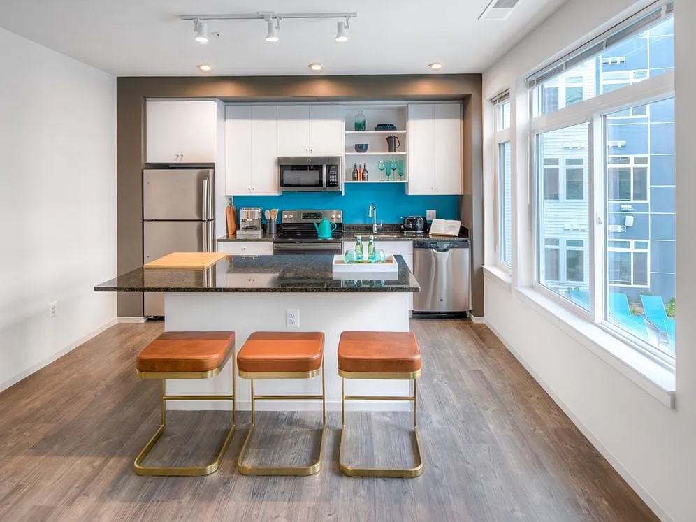 Kitchen with white cabinetry, granite countertops, island, stainless steel appliances and hard surface flooring - AVA Wheaton