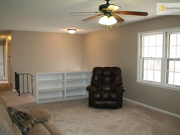 Living room features built in book shelves, new carpet and newer ceiling fan.