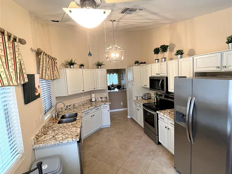 Kitchen with newly updated ivory cabinets and new granite plus 1 of 3 tables to dine at. (Kitchen/Dining/Livingroom/Patio)