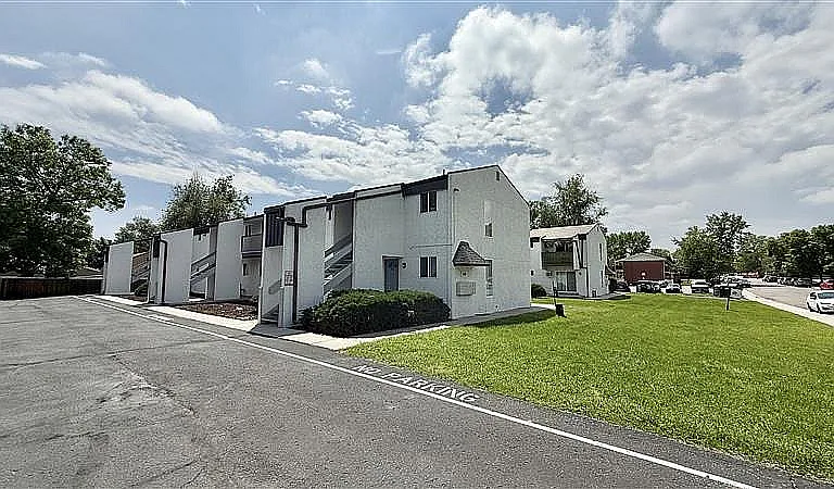 Charming apartment complex with modern architecture, lush green lawn, and ample parking in a serene neighborhood setting.