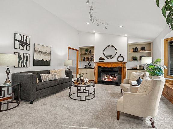 The expansive formal living room features granite surround wood burning fireplace with custom wood mantel flanked with built-ins.>